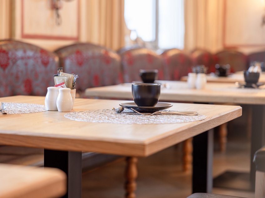 Willkommen im Hotel in Neustift im Stubaital! Leerer Tisch im Restaurant mit Platzset, Tasse und Gewürzbehältern