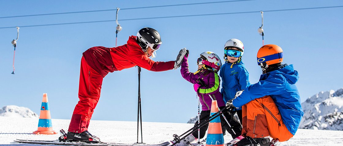 Willkommen im Hotel in Neustift im Stubaital! Skilehrer gibt Kindern auf schneebedeckter Piste High Five