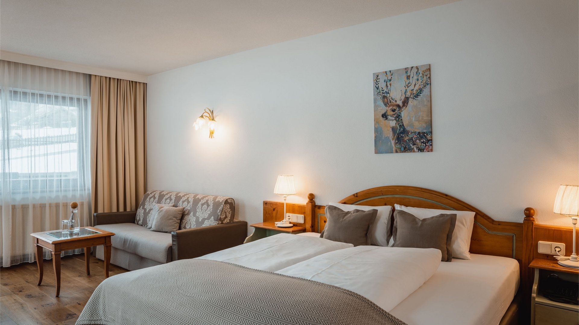 Willkommen im Hotel in Neustift im Stubaital! Gemütliches Hotelzimmer mit Doppelbett, Sofa, Holzmöbeln und Hirschbild an der Wand